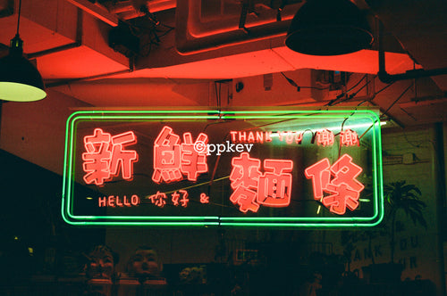 A glowing rectangular neon sign with Chinese characters and English text reading 'THANK YOU' and 'HELLO', mounted in a dimly lit interior with red ambient lighting.